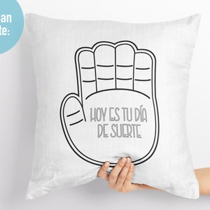 K&ouml;nnte beinhalten: Wei&szlig;es Kissen mit einer schwarzen Umrandung einer Hand mit dem Text "HOY ES TU DIA DE SUERTE" in Schwarz.