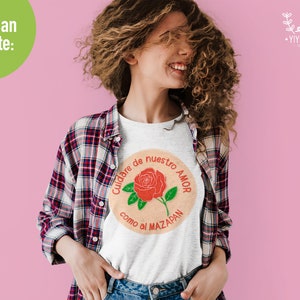 K&ouml;nnte beinhalten: Ein wei&szlig;es T-Shirt mit einer roten Rose und dem Text "Cuidare de nuestro amor como al mazap&aacute;n" auf der Vorderseite.