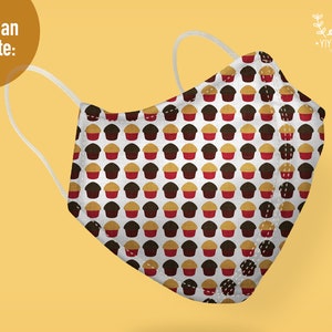 May include: A white face mask featuring a repeating pattern of small brown and red cupcakes. The mask has two white elastic ear loops and a structured, pointed front seam. The text "You Can Create:" appears in the upper left corner of the image.