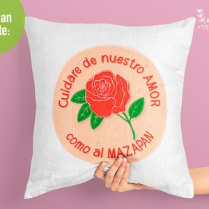 K&ouml;nnte beinhalten: Ein wei&szlig;es Kissen mit einer roten gestickten Rose und dem Text "Cuidare de nuestro AMOR como al MAZAPAN".
