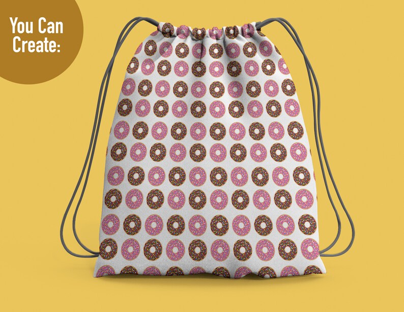 May include: A white drawstring backpack featuring a repeating pattern of donuts with pink frosting and multi-colored sprinkles, along with chocolate frosted donuts with sprinkles. The bag has dark gray cord straps and the text You Can Create.