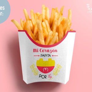 May include: A white paper container filled with golden french fries. The container has a red rim and a Spanish-language design that says "Mi Corazon Papita" with a heart and a small illustration of a potato. The text "Por Ti" is also printed on the container.