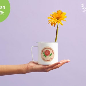 K&ouml;nnte beinhalten: Eine wei&szlig;e Tasse mit einem runden Aufkleber, auf dem in Spanisch "Cuidar de nuestro amor como di Mazadan" steht. Der Aufkleber zeigt eine rote Rose mit gr&uuml;nen Bl&auml;ttern. In der Tasse befindet sich eine gelbe G&auml;nsebl&uuml;mchen.