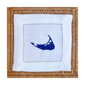 May include: White linen cocktail napkin with a blue embroidered outline of the island of Martha's Vineyard.