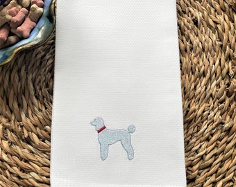May include: White kitchen towel with a blue embroidered poodle wearing a red collar.