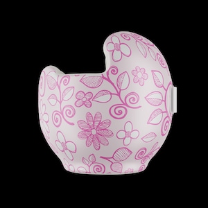 以下が含まれることがあります： ピンクの花柄が施されたピンクのヘルメット。ヘルメットには白いストラップと白いバックルが付いています。