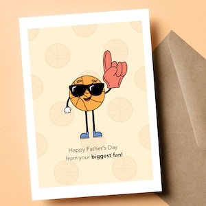 May include: A card with a cartoon basketball wearing sunglasses and a red glove, with the text "Happy Father's Day from your biggest fan!"