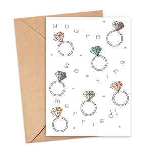 May include: A white card with the text "You're getting married!" surrounded by illustrations of rings with diamonds in various colors.