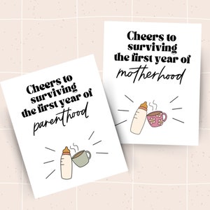 May include: Two white cards with black text and illustrations. The text on the top card reads "Cheers to surviving the first year of motherhood". The text on the bottom card reads "Cheers to surviving the first year of parenthood". Both cards feature a cartoon illustration of a baby bottle and a coffee cup.