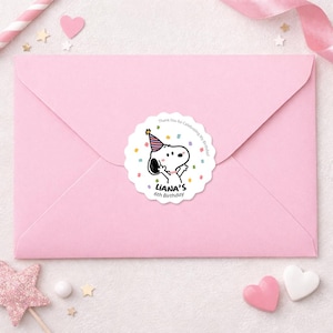 May include: A pink envelope with a round sticker featuring Snoopy wearing a party hat. The sticker says "LIANA'S 6th Birthday" and "Thank You for Celebrating My Birthday!" with confetti. Decorative elements include hearts and stars.