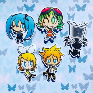 May include: Six colorful cartoon character stickers featuring anime-style characters with large eyes and bright colors. The characters are a girl with blue hair, a girl with green hair, a girl with yellow hair, a boy with yellow hair, and a robot with a television screen for a head.