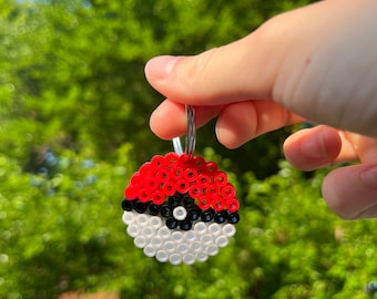May include: A red and white Pokeball keychain made of plastic beads. The keychain is attached to a silver metal ring.
