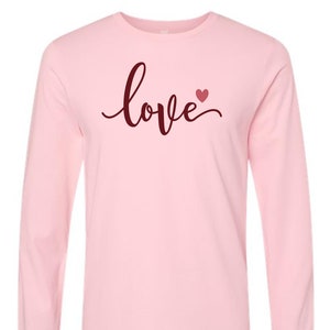 May include: Pink long-sleeve t-shirt with the word "love" in burgundy script with a small burgundy heart.