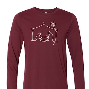May include: A maroon long-sleeve t-shirt with a white outline of the nativity scene, including a star, a manger, and two figures.