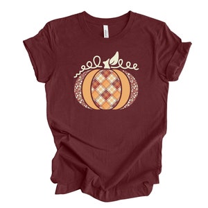 May include: A maroon t-shirt with a graphic of a pumpkin with a plaid pattern and the text "well, hello" above it.