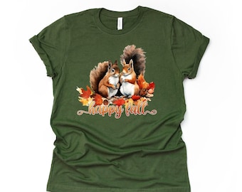 May include: A green t-shirt with a watercolor illustration of two squirrels sitting on a pile of autumn leaves. The text "happy fall" is written in orange below the squirrels.