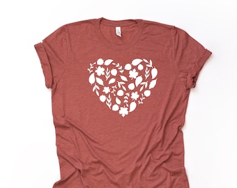 May include: A maroon t-shirt with a white heart-shaped design made of leaves and flowers.