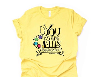 May include: Yellow t-shirt with a black and white graphic design featuring a paintbrush, paint palette, and the text "You are His Masterpiece Ephesians 2:10".