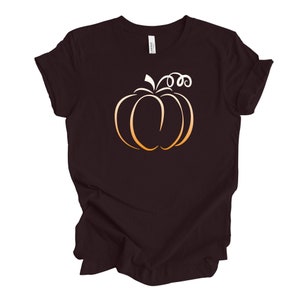May include: A dark brown t-shirt with a gold outline of a pumpkin on the front.