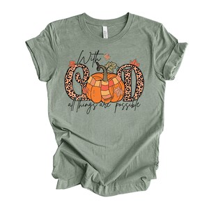 May include: Sage green t-shirt with a graphic of two pumpkins with a leopard print background. The text "With God all things are possible" is printed below the pumpkins.