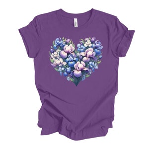 Puede incluir: Camiseta morada con un diseño en forma de corazón hecho de flores de iris azules, blancas y moradas.