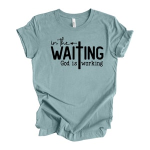 May include: A light blue t-shirt with a black graphic that says "in the ♥ waiting God is working" with a cross.