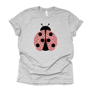 May include: A gray t-shirt with a black and red ladybug design. The ladybug's wings are filled with a red mandala pattern.