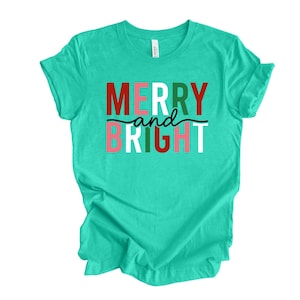 May include: A turquoise t-shirt with the text "Merry and Bright" in red, green, white, and pink letters.