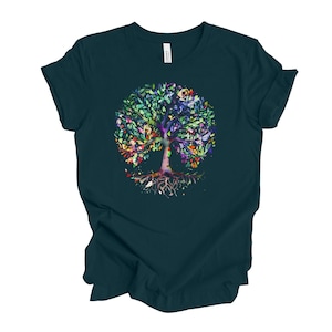May include: A dark teal t-shirt with a colorful watercolor tree design. The tree has a thick trunk and many branches with green, blue, purple, yellow, and orange leaves. The roots of the tree are visible and extend out from the trunk.