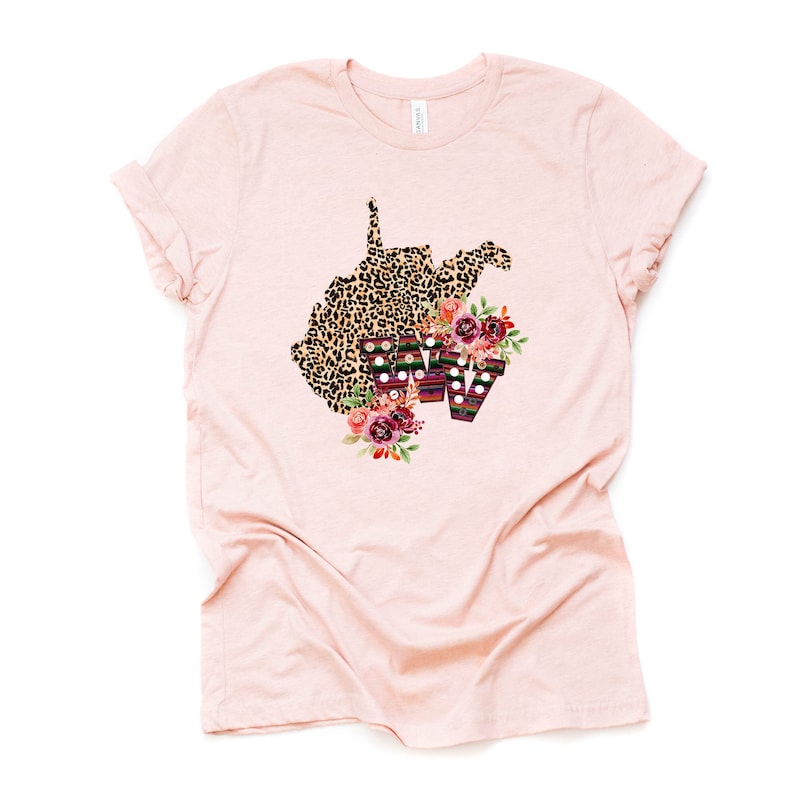 May include: A pink t-shirt with a leopard print outline of the state of West Virginia with the letters WV in a colorful patterned design and floral accents.