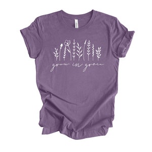 May include: A purple t-shirt with a white graphic of stylized flowers and the text "grow in grace".