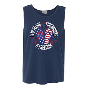May include: A navy blue sleeveless shirt with a white circle graphic featuring red, white, and blue flip flops and fireworks. The text "Flip Flops & Fireworks & Freedom" is written around the graphic.