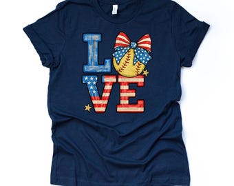 May include: Navy blue t-shirt with a patriotic "LOVE" design. The "L" and "V" are red and white striped, the "O" is a baseball with a red, white, and blue bow, and the "E" is blue with white stars. Gold stars accent the design.