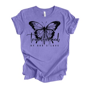 Peut inclure: T-shirt violet avec un motif de papillon noir et le texte "transform&eacute; par l'amour de Dieu".