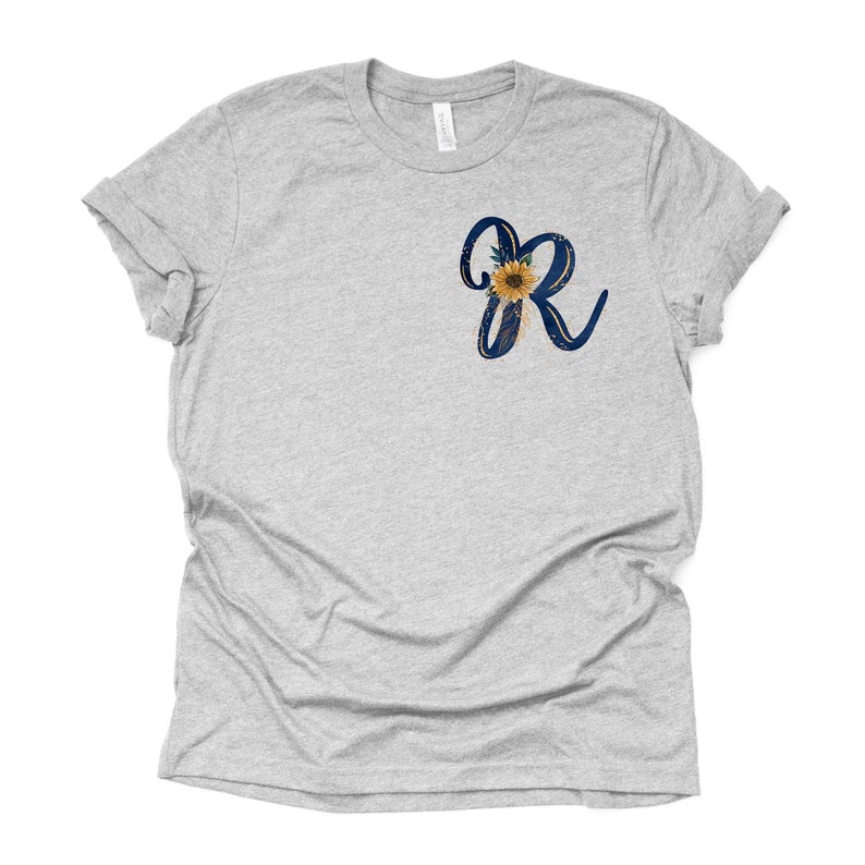May include: A heather grey t-shirt with a blue and gold sunflower graphic featuring the letter "R".