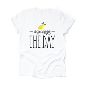 May include: White t-shirt with a yellow lemon graphic and the text "squeeze the day" in black.