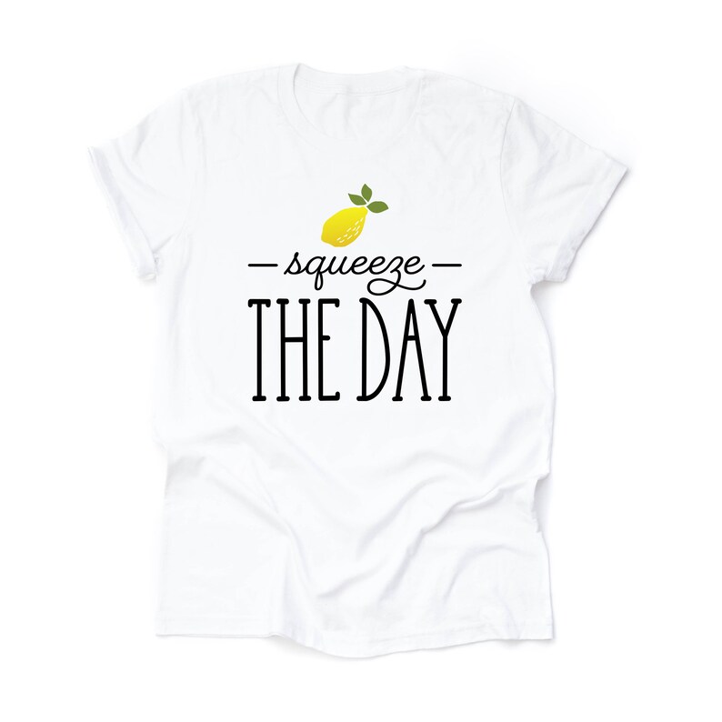 May include: White t-shirt with a yellow lemon graphic and the text "squeeze the day" in black.