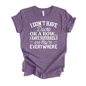 Peut inclure: T-shirt violet avec un texte blanc qui dit "Je n'ai pas de canards ou une rang&eacute;e... J'ai des &eacute;cureuils - et ils sont partout"