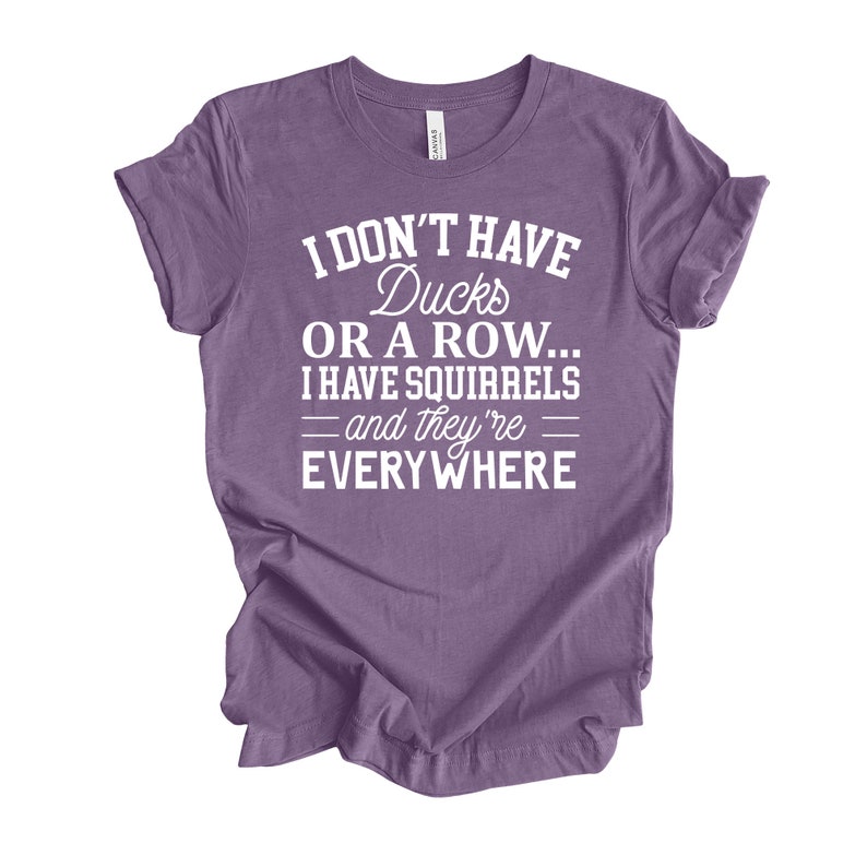 Peut inclure: T-shirt violet avec un texte blanc qui dit "Je n'ai pas de canards ou une rang&eacute;e... J'ai des &eacute;cureuils - et ils sont partout"