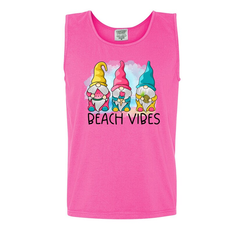 Pu&ograve; includere: Canotta rosa senza maniche con una grafica di tre gnomi che tengono dolcetti estivi. Gli gnomi indossano cappelli colorati e sono in piedi davanti a una scena di spiaggia. Il testo "Beach Vibes" &egrave; stampato sotto gli gnomi.