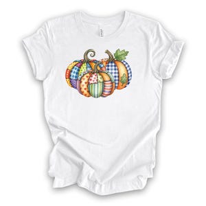 Pu&ograve; includere: T-shirt bianco con un design di zucche colorate. Le zucche sono decorate con vari motivi, tra cui pois, cuori e strisce. Ideale per le celebrazioni autunnali.
