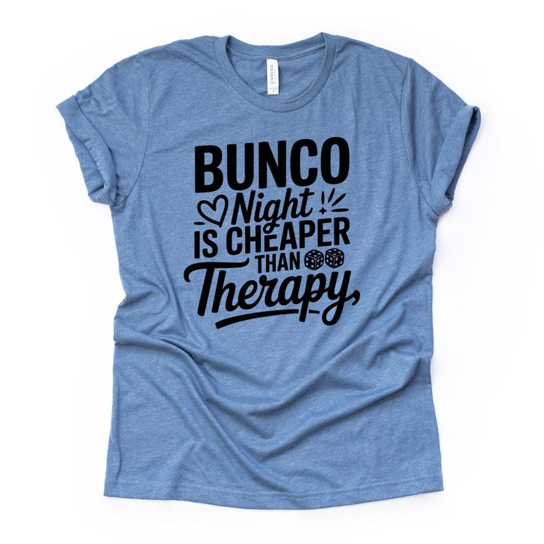 K&ouml;nnte beinhalten: Hellblaues T-Shirt mit dem schwarzen Text "Bunco Night is Cheaper Than Therapy". Der Text enth&auml;lt ein Herz, W&uuml;rfel und einen Blitz. Das T-Shirt ist aus weichem Material.