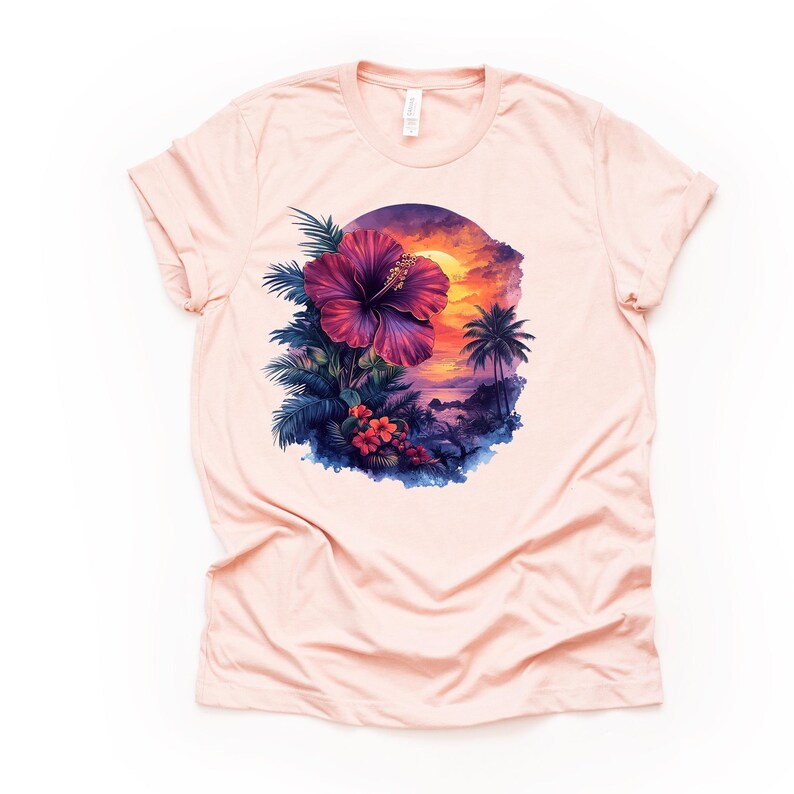 May include: A light pink t-shirt featuring a vibrant tropical design. The graphic includes a large, deep purple hibiscus flower, lush green and blue foliage, and a sunset scene with palm trees. The shirt is made of soft material.