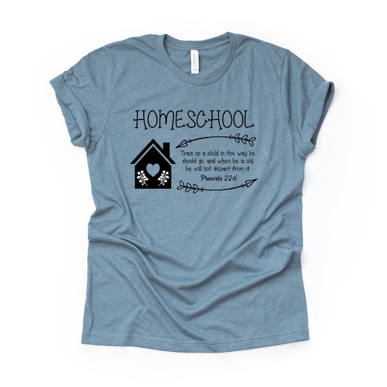 Puede incluir: Una camiseta azul claro con el texto "HOMESCHOOL" y una casa negra con un coraz&oacute;n. El texto "Train up a child in the way he should go and when he is old, he will not depart from it. Proverbs 22:6" tambi&eacute;n est&aacute; impreso en la camiseta.