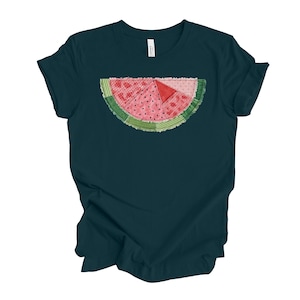 May include: Dark teal t-shirt featuring a watermelon slice design. The watermelon slice is pink with black seeds, a red triangle, and a green rind. The design is centered on the front of the shirt.