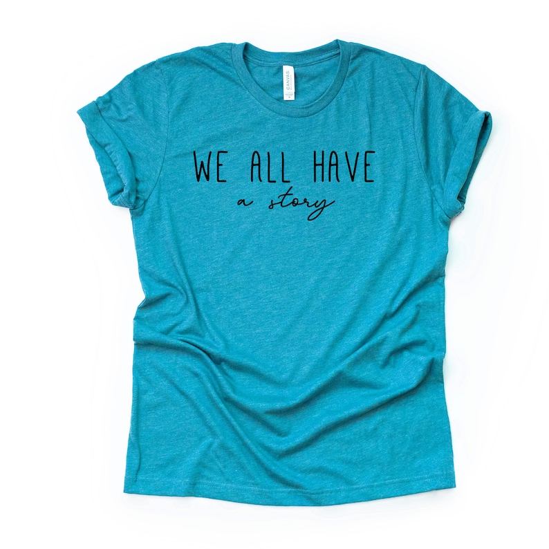 May include: A teal blue t-shirt with the text "WE ALL HAVE a story" printed in black.
