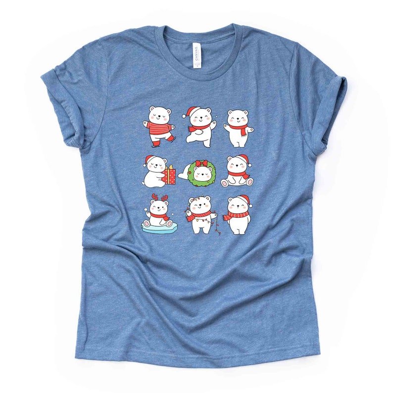 Pode incluir: Uma camiseta azul com um urso polar branco vestindo um chap&eacute;u de Papai Noel vermelho e uma echarpe, segurando um presente e em p&eacute; em uma prancha de surf azul e branca. A camiseta tem um tema natalino com outros ursos polares vestindo diferentes acess&oacute;rios natalinos.