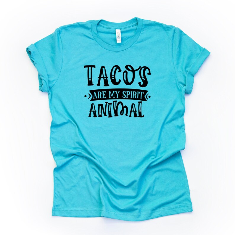 Puede incluir: Una camiseta azul turquesa con texto negro que dice "Tacos are my spirit animal".