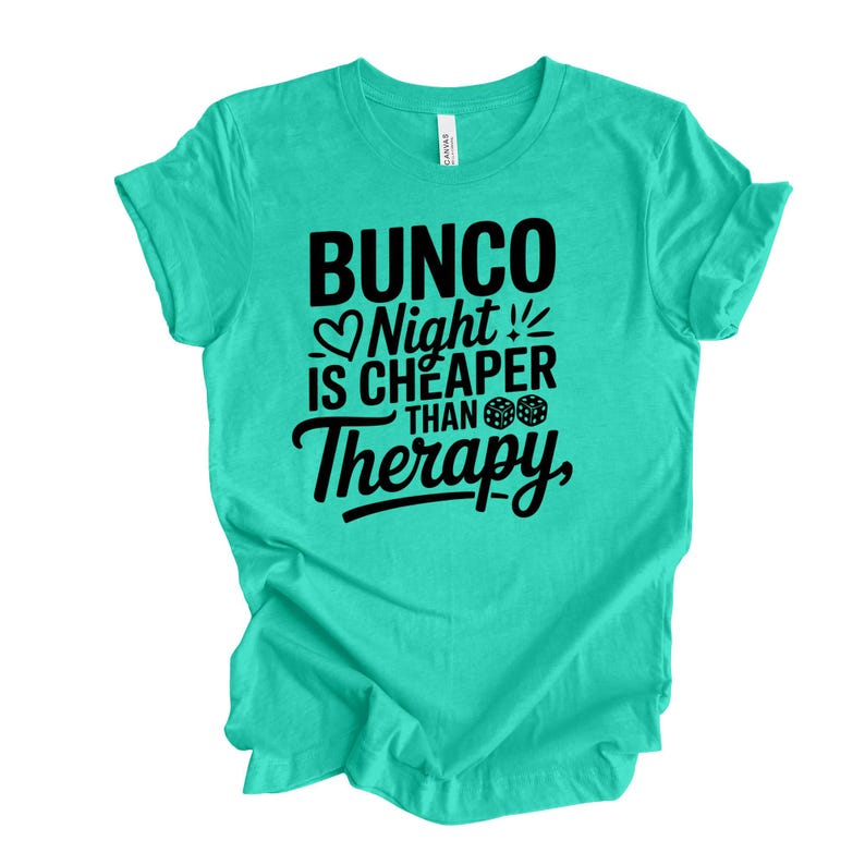 K&ouml;nnte beinhalten: Ein t&uuml;rkisfarbenes T-Shirt mit dem Text "Bunco Night is Cheaper Than Therapy" in schwarzer Schrift. Das Design beinhaltet ein Herz, W&uuml;rfel und Ausrufezeichen. Das Shirt ist aus einem weichen Material.