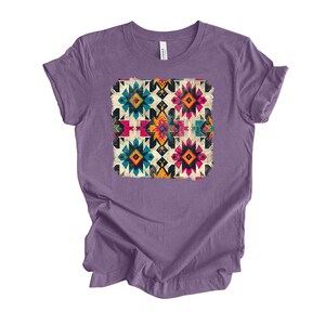 Pu&ograve; includere: Maglietta viola con un motivo geometrico colorato stampato sul davanti. Il motivo presenta una variet&agrave; di forme e colori, tra cui rosso, blu, giallo e verde.